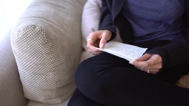 Μια γυναίκα κάθεται στον καναπέ και διαβάζει ένα γράμμα. - Πλάνα, βίντεο