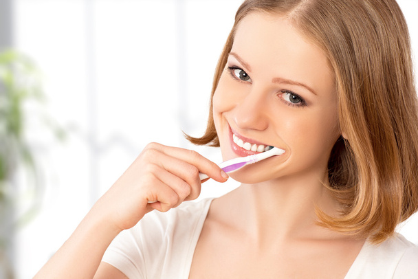 happy woman brushing her teeth with a toothbrush - Foto, Imagem