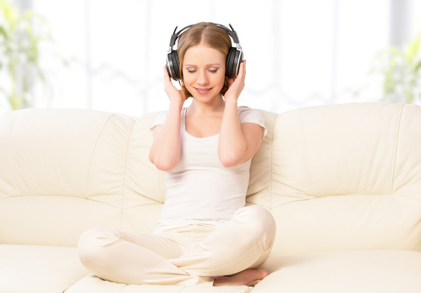 beautiful girl in headphones enjoying music at home on the couch - Photo, Image