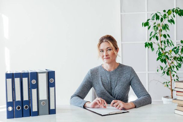 femme en costume d'affaires au travail au bureau à une table avec des livres et des documents - Photo, image