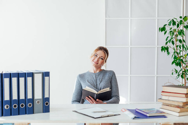 woman in business suit at work in office at a table with books and documents - Foto, Imagem