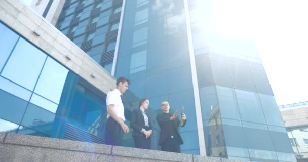 Skupina mladých profesionálních manažerů finančníků stojí v pozadí mrakodrapu v odrazu slunce objednané, mluví o podnikání. Tým investorů diskutuje o dohodě, vyjednává v neformálním prostředí - Záběry, video