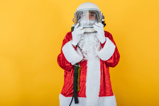 Santa Claus with astronaut helmet on yellow background. Christmas concept - Photo, Image