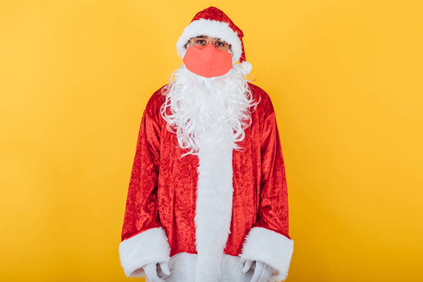 Der Weihnachtsmann trägt eine rote Gesichtsmaske auf gelbem Hintergrund. Weihnachtskonzept - Foto, Bild