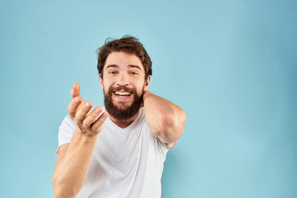 Vrolijke man gebaren met zijn handen emoties bijgesneden uitzicht op blauwe achtergrond studio - Foto, afbeelding