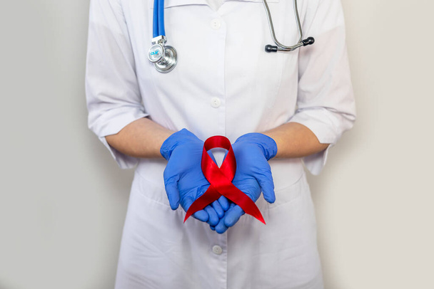 Red ribbon for aids world day support, close up of doctor hand in glove. - Fotoğraf, Görsel