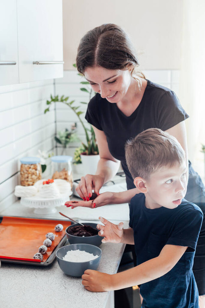 Mamá pastelera e hijo cocinan pasteles dulces en la cocina - Foto, Imagen