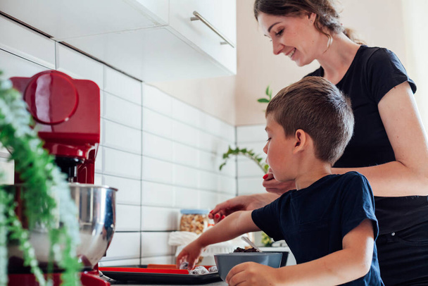 Mutter Konditorin und Sohn kochen süße Kuchen in der Küche - Foto, Bild