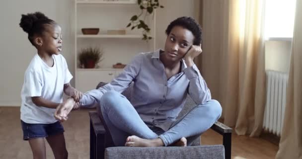 jong moe single afrikaanse moeder lijdt aan hoofdpijn zitten op de bank gevoel van stress, terwijl haar dochter rent rond haar schreeuwen aanraken moeder, zwart vrouwelijke babysitter uitgeput door lawaaierige kind meisje - Video