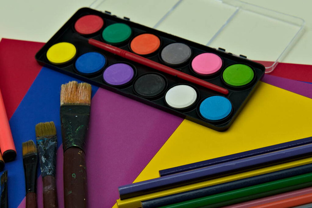 Kunstbenodigdheden voor creatieve geesten, penselen, aquarellen, potloden en gekleurd karton.  - Foto, afbeelding