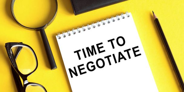 Time to negotiate on a notebook on yellow desk - Foto, Imagen