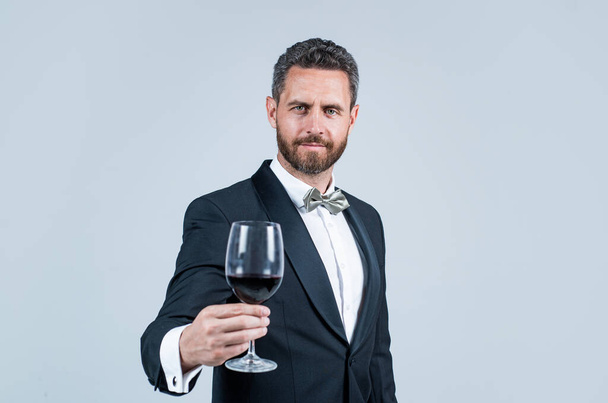 man wear office costume. formal event. businessman drink red wine. cheers for happy valentines day. alcohol drinking. handsome male on romantic date. unshaven man with wine glass. sommelier - Foto, Bild
