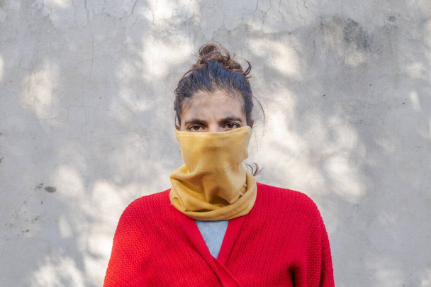 fiatal nő arca borítja egy sárga ruhadarab szürke háttér közepes lövés - Fotó, kép