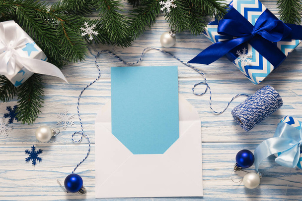青い木製の背景にモックアップクリスマスグリーティングカードと贈り物。季節の挨拶のテンプレート. - 写真・画像