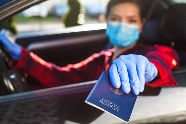 Junge Frau mit blauem Pass durch die Autoscheibe, Kontrolle durch Grenzschutzpersonal, Coronavirus-Immunitätsausweis, Gesundheitspass, Sicherheit und Schutz vor Ausbreitung und Übertragung des Virus - Foto, Bild