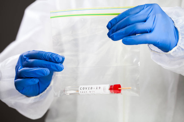 COVID-19ウイルス疾患自己綿棒試験片キット、喉または鼻綿棒ウイルス試験片採取装置付きの試験管を含むプラスチック製の袋を有する医学研究所の科学者、コロナウイルス  - 写真・画像