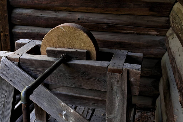 Антикварний шліфувальний камінь в дереві, залізному і кам'яному, зроблений для загострення ножів та інших металевих інструментів
.  - Фото, зображення