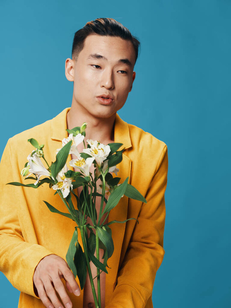 Mężczyzna z bukietem kwiatów w ręku na niebieskim tle i żółtą kurtką Copy Space - Zdjęcie, obraz