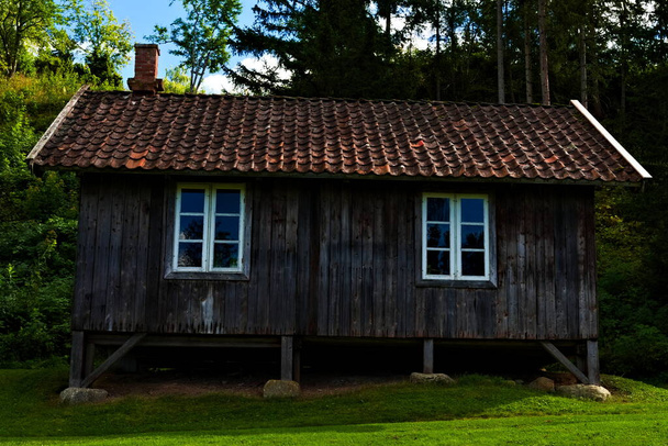 Покинутий старий дерев'яний фермерський будинок з глиняною черепицею та вивітреними колодами
. - Фото, зображення