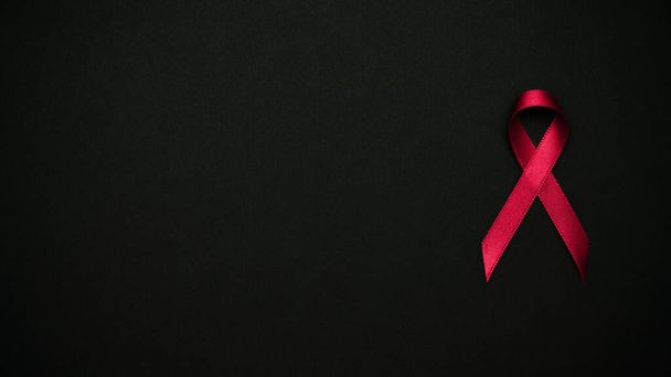 Soporte para el VIH. Símbolo de cinta roja en el día mundial del VIH sobre fondo negro. Ayudas a la concienciación y cáncer. Envejecimiento Salud concepto de mes - Foto, Imagen