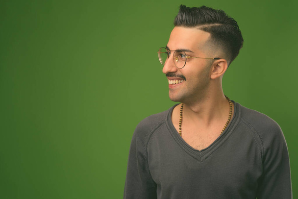 Junger schöner iranischer Mann mit Schnurrbart vor grünem Hintergrund - Foto, Bild