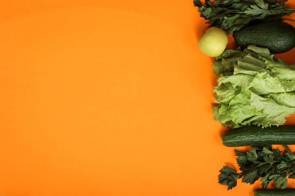 Greens and green vegetables on orange background, copy space. Vegetarian food - Φωτογραφία, εικόνα
