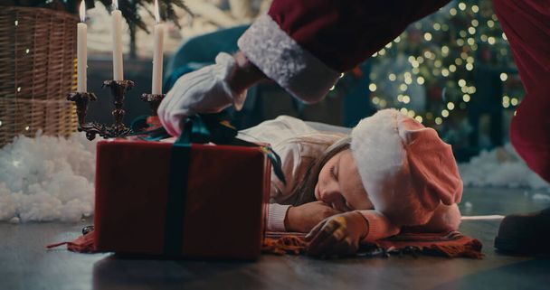 Crop Santa Claus giving present to sleeping girl - Photo, Image