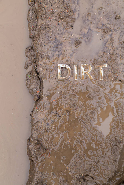 the word mud imprinted in wet dirt road surface and puddle - close-up with selective focus in flat lay perspective. - Photo, Image