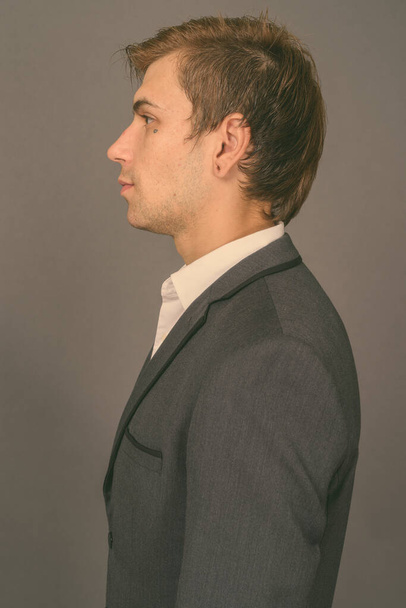 Портрет молодого привлекательного бизнесмена на сером фоне - Фото, изображение