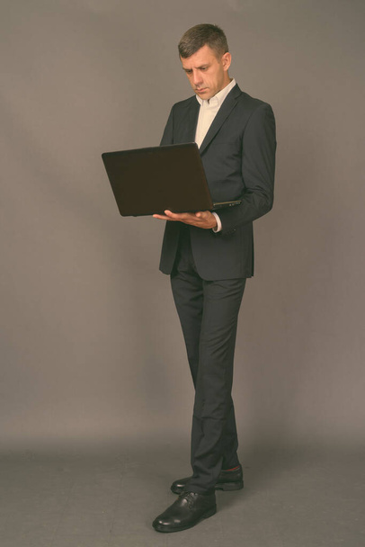 Handsome businessman with short hair against gray background - Foto, Imagem