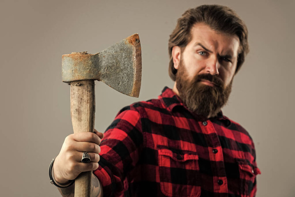 woodcutter in a plaid shirt. Lumberjack brutal bearded man in red checkered shirt. concept of shaving. halloween. man holds an ax in his hand. bearded lumberjack with an axe. selective focus - Foto, imagen