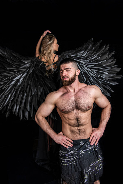 angelo con ali nere e rappresentante della razza umana su sfondo nero - Foto, immagini