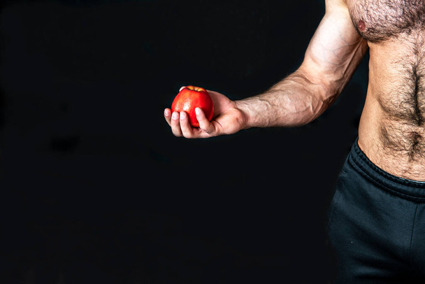 main sportive masculine tenant pomme rouge sur fond noir - Photo, image