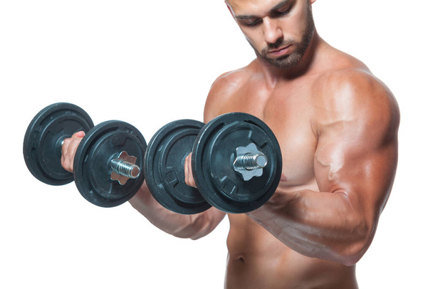 Sexy athletic man is showing muscular body with dumbbells standing with his head down, isolated over white background - Valokuva, kuva