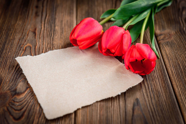 Георгиевская лента, красные тюльпаны и бумажная открытка на деревянном фоне. День Победы или День защитника Отечества. - Фото, изображение