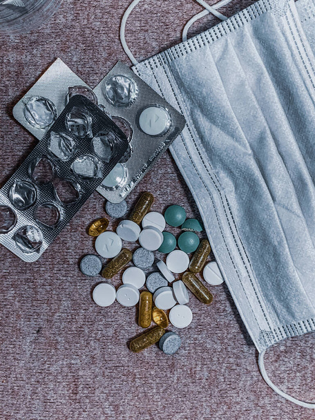 A closeup shot of medicine tablets and a protective mask- COVID-19 - Zdjęcie, obraz