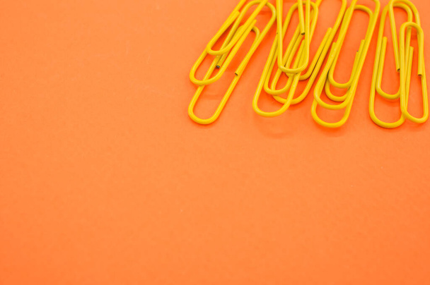 A closeup of yellow paperclips on orange background with space for your text - Φωτογραφία, εικόνα