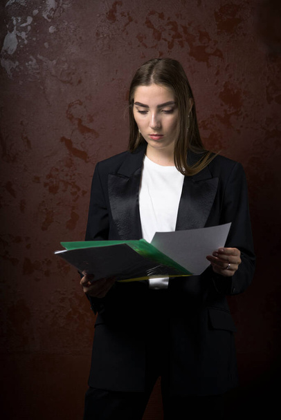 Jeune mannequin femme posant avec des papiers dans des vêtements élégants. - Photo, image