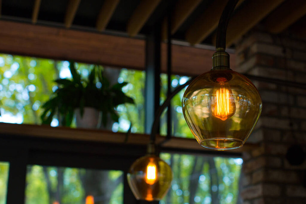 店内の天井にはLEDエジソンランプが設置されたコーヒーカラーの明るいガラスランプ。レストランのインテリア、レトロ. - 写真・画像