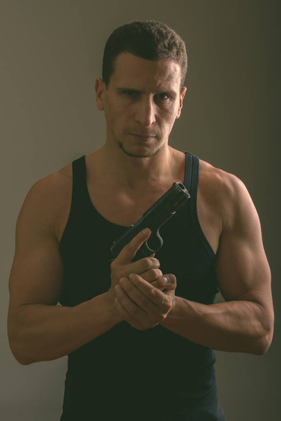 Studio ujęcie młodego muskularnego Persa trzymającego pistolet gotowy do akcji - Zdjęcie, obraz