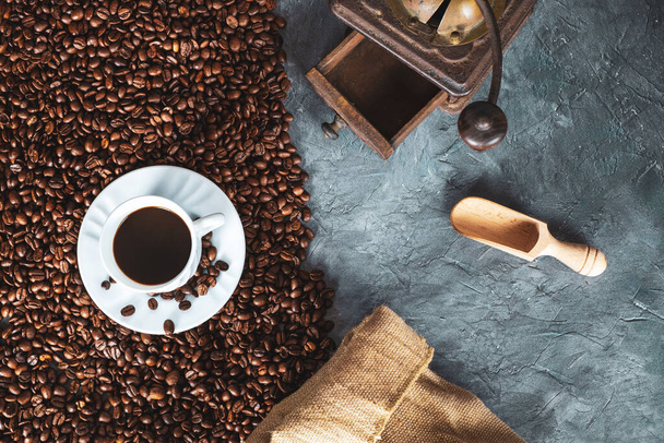 おいしいコーヒー豆と織り袋、暗い石の背景にレトロなコーヒーグラインダー - 写真・画像