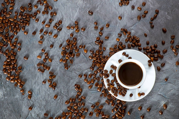 Deliciosos granos de café y taza de café, pila de café sobre fondo de piedra negra - Foto, imagen
