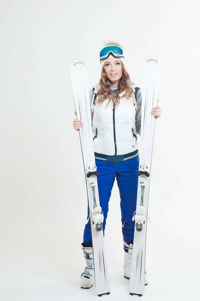 帽子とスキーのためのマスクに笑みを浮かべて女の子のスキーヤー。スキーやアウトドア活動のための服を着た若い女性. - 写真・画像