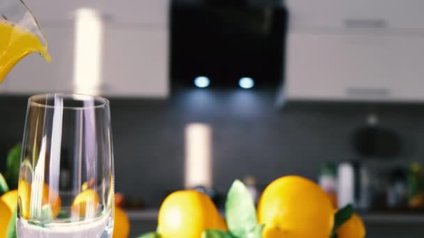 Апельсиновый сок наливается в стакан на белом столе - Кадры, видео