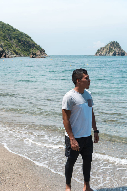 Um hispânico com uma t-shirt branca na praia com vista para o mar. O conceito de pessoas - Foto, Imagem