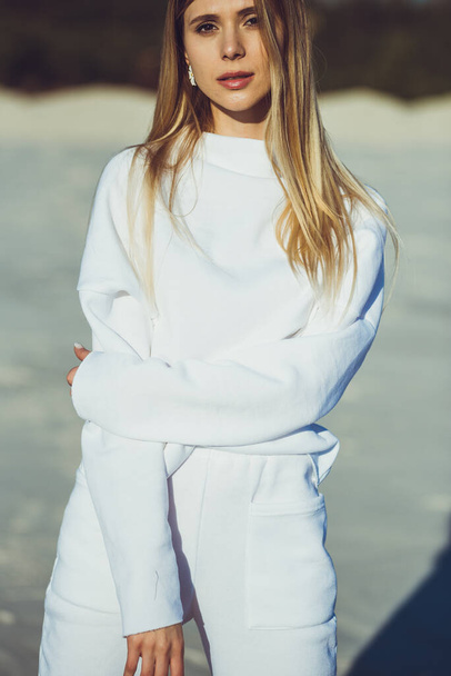 Portrait of beautiful blonde woman. Fashion woman wearing white warm clothes outdoor on the beach. - Photo, Image