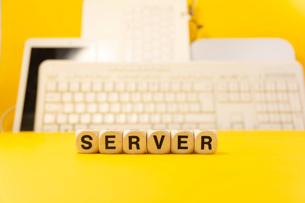 The word server written with real wooden dices in front of a yellow background with computers and keyboard - Φωτογραφία, εικόνα