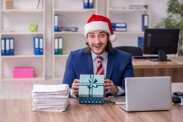 Jonge mannelijke werknemer werkt in het kantoor op kerstavond - Foto, afbeelding