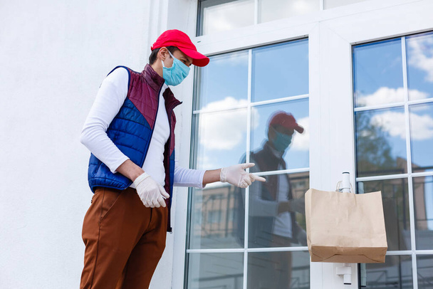 Grocery delivery man wearing medical gloves and face mask. Online shopping and delivery for grocerys, wine and food. Self Quarantine during coronavirus pandemic. Food delivery service courier - Photo, Image