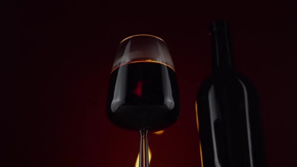 Wijn in wijnglas op achtergrond met brandend vuur, glazen fles - Video